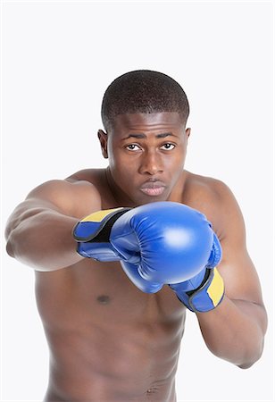 simsearch:693-06379482,k - Portrait of an African American boxer punching over gray background Foto de stock - Sin royalties Premium, Código: 693-06379506