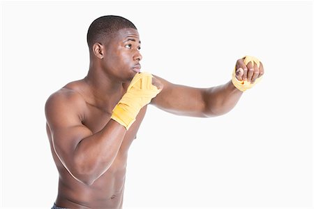 simsearch:693-06379534,k - African American male boxer kickboxing over gray background Stock Photo - Premium Royalty-Free, Code: 693-06379509