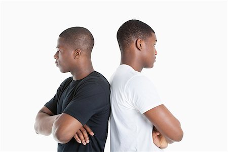 simsearch:693-06379524,k - Two male friends standing back to back over gray background Foto de stock - Royalty Free Premium, Número: 693-06379524