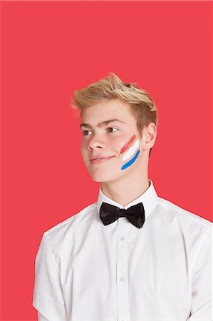 Happy young man with Dutch flag painted on his face over red background Foto de stock - Sin royalties Premium, Código: 693-06379549