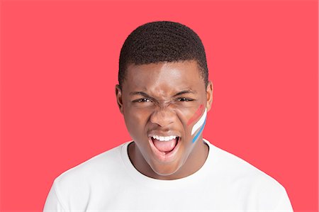 painted face - Portrait of an aggressive young man with Dutch flag on his face over red background Stock Photo - Premium Royalty-Free, Code: 693-06379551