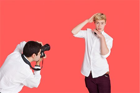 photographer (male) - Male actor being photographed by paparazzi over red background Stock Photo - Premium Royalty-Free, Code: 693-06379562