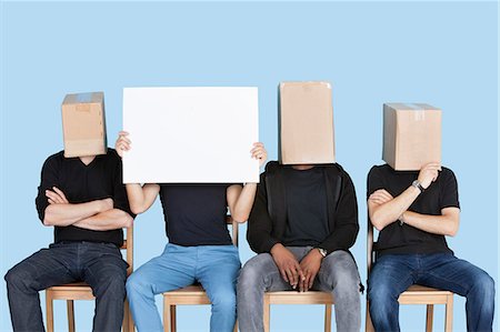 face card - Man holding blank cardboard with male friends faces covered with boxes over blue background Foto de stock - Sin royalties Premium, Código: 693-06379593