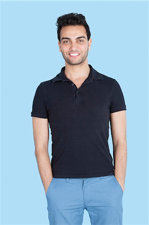 portrait studio white tshirt - Portrait of a handsome man with hands in pockets over blue background Foto de stock - Sin royalties Premium, Código: 693-06379606