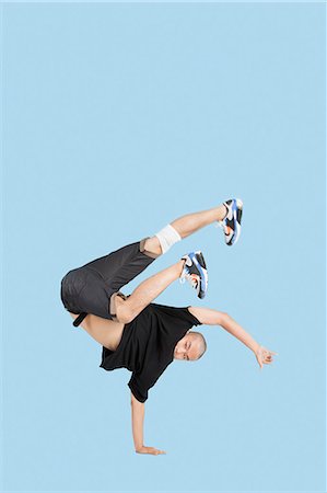 Male break dancer performing handstand over blue background Foto de stock - Sin royalties Premium, Código: 693-06379600