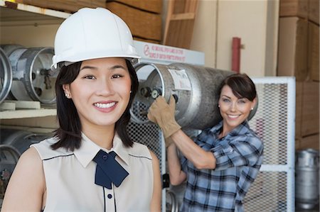 fabrikarbeiter - Porträt Frau lächelnd mit weiblichen Industriearbeiter mit Propan Zylinder im Hintergrund Stockbilder - Premium RF Lizenzfrei, Bildnummer: 693-06379676