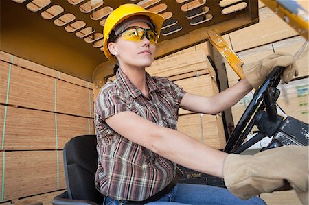 forklift truck - Female industrial worker driving forklift truck with stacked wooden planks in background Foto de stock - Sin royalties Premium, Código: 693-06379686