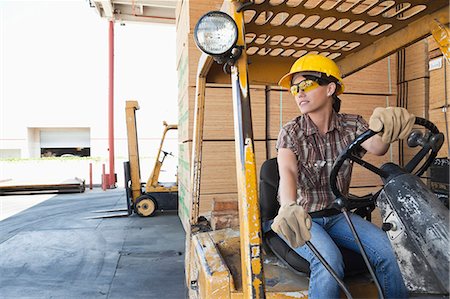 empilhadeira - Female industrial worker looking away while driving forklift truck Foto de stock - Royalty Free Premium, Número: 693-06379687