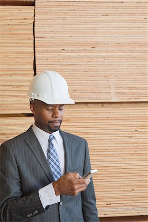 simsearch:693-06379667,k - Afroamerikaner männlichen Ingenieur mit Handy mit gestapelten Holzbohlen im Hintergrund Stockbilder - Premium RF Lizenzfrei, Bildnummer: 693-06379697