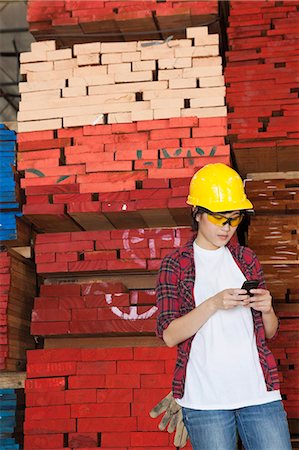 simsearch:693-06379667,k - Asian female industrial worker using cell phone with stacked wooden planks in background Foto de stock - Sin royalties Premium, Código: 693-06379731