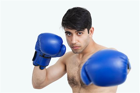 Bildnis eines indischen nackter Oberkörper Mannes tragen blaue Boxhandschuhe gegen grauen Hintergrund Stockbilder - Premium RF Lizenzfrei, Bildnummer: 693-06379797