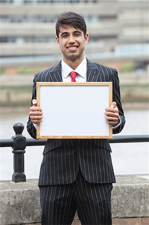 Portrait de jeune homme d'affaires indien, tenant une pancarte blanche Photographie de stock - Premium Libres de Droits, Code: 693-06379813