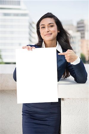 Portrait of a young Indian businesswoman pointing towards Moodboard sign Stock Photo - Premium Royalty-Free, Code: 693-06379895