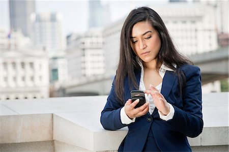 female holding a mobile phone - Young Indian businesswoman using smart phone Stock Photo - Premium Royalty-Free, Code: 693-06379892