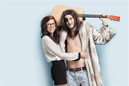 funky - Portrait of young man holding guitar while standing with happy woman against light blue background Foto de stock - Sin royalties Premium, Código: 693-06379998