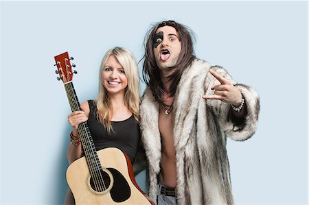 fur coats for women image - Portrait of happy young man gesturing with woman holding guitar against light blue background Stock Photo - Premium Royalty-Free, Code: 693-06379999