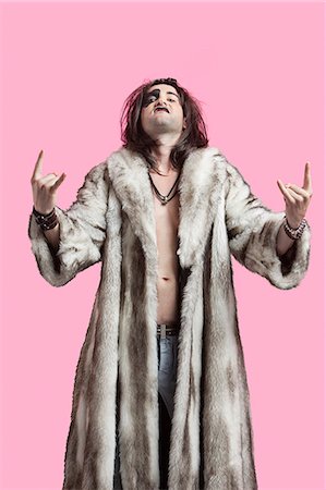 rock - Portrait of young man in fur coat gesturing rock music sign over pink background Stock Photo - Premium Royalty-Free, Code: 693-06380016