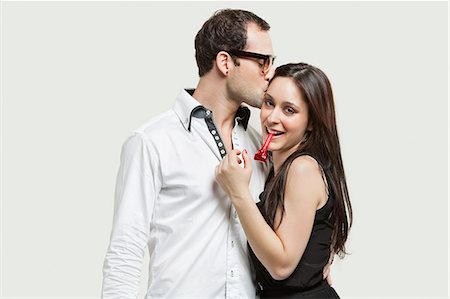 Young couple with party puffer against gray background Stock Photo - Premium Royalty-Free, Code: 693-06380033