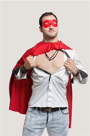 position - Young man in superhero costume standing against gray background Stock Photo - Premium Royalty-Free, Code: 693-06380041