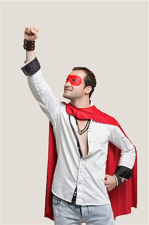 superhero - Young man in superhero costume with hand raised against gray background Stock Photo - Premium Royalty-Free, Code: 693-06380043