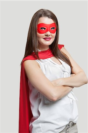 Portrait of a young woman in super hero costume over gray background Stock Photo - Premium Royalty-Free, Code: 693-06380079