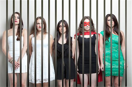 prison photograph - Woman in superhero costume with female friends standing behinds prison bars Stock Photo - Premium Royalty-Free, Code: 693-06403203