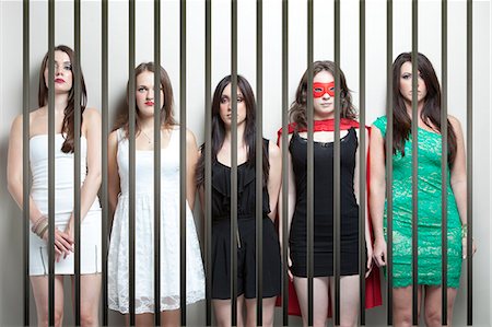 Woman in superhero costume with female friends standing behinds prison bars Foto de stock - Sin royalties Premium, Código: 693-06403203