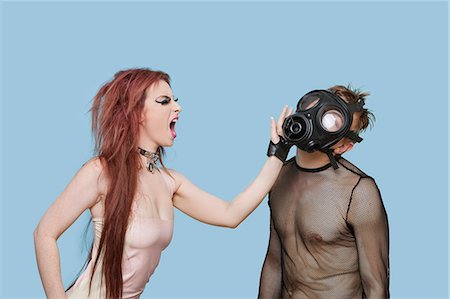 rebel woman - Funky young woman slapping man in gas mask over blue background Stock Photo - Premium Royalty-Free, Code: 693-06403225