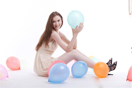 female holding balloons - Beautiful young woman in dress on floor with balloons against white background Stock Photo - Premium Royalty-Free, Code: 693-06403262