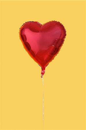 Red heart shaped balloon over yellow background Stock Photo - Premium Royalty-Free, Code: 693-06403291