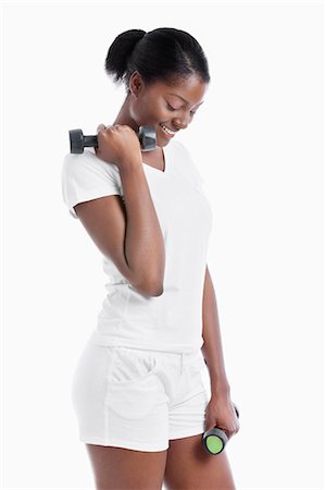 Thoughtful African American young woman with dumbbells standing over white background Stock Photo - Premium Royalty-Free, Code: 693-06403316