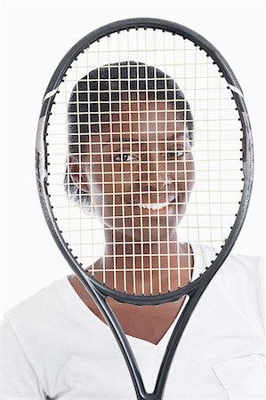 Portrait of an African American young woman looking through tennis racket Stock Photo - Premium Royalty-Free, Code: 693-06403322