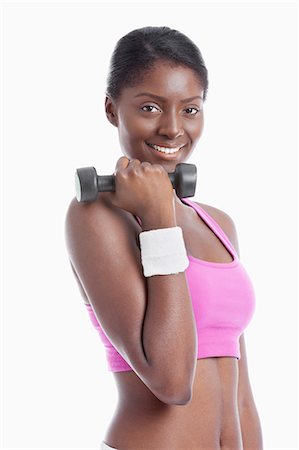 Portrait of happy young woman holding dumbbell over white background Stock Photo - Premium Royalty-Free, Code: 693-06403330