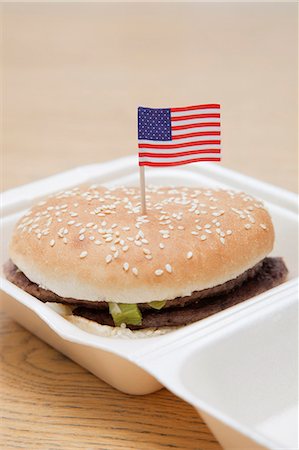 Grilled hamburger with American flag decoration on wooden surface Fotografie stock - Premium Royalty-Free, Codice: 693-06403332