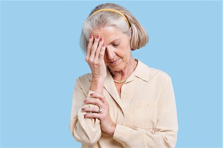 sick senior - Senior woman suffering from headache against blue background Stock Photo - Premium Royalty-Free, Code: 693-06403408