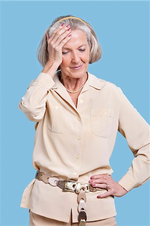 douleur - Femme senior en employés occasionnels souffrant de maux de tête sur fond bleu Photographie de stock - Premium Libres de Droits, Code: 693-06403401