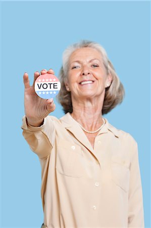 démocratie - Portrait de femme senior tenant un badge d'élection sur fond bleu Photographie de stock - Premium Libres de Droits, Code: 693-06403426