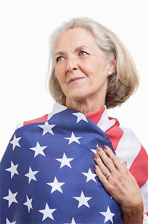 Senior woman wrapped in American flag against white background Stock Photo - Premium Royalty-Free, Code: 693-06403469