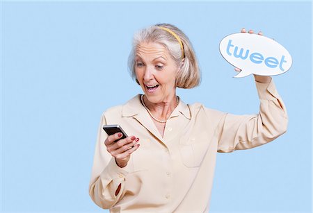 enthusiastic senior woman - Senior woman in casuals using social media on her Smartphone against blue background Stock Photo - Premium Royalty-Free, Code: 693-06403482