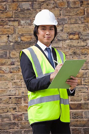 Portrait of young supervisor holding clipboard at construction site Stock Photo - Premium Royalty-Free, Code: 693-06403494