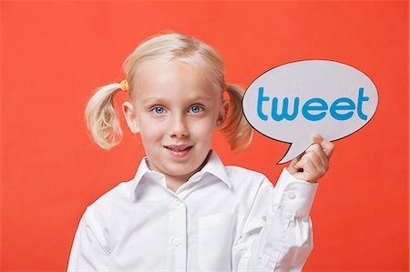 simsearch:693-06324793,k - Portrait of a young girl holding tweet bubble against orange background Fotografie stock - Premium Royalty-Free, Codice: 693-06403517