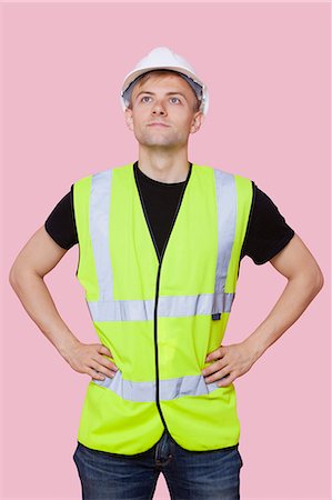 simsearch:693-06379322,k - Handsome construction worker with hands on hips over pink background Foto de stock - Sin royalties Premium, Código: 693-06403522