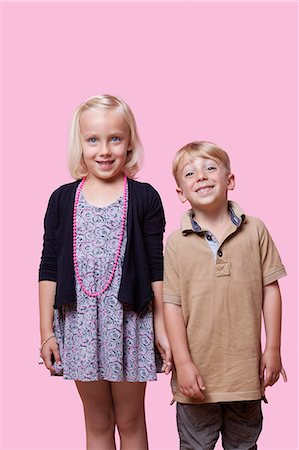 Portrait of happy brother and sister standing over pink background Stock Photo - Premium Royalty-Free, Code: 693-06403538