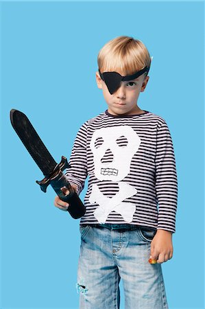 sword - Portrait of a young boy in pirate costume holding sword over blue background Stock Photo - Premium Royalty-Free, Code: 693-06403564