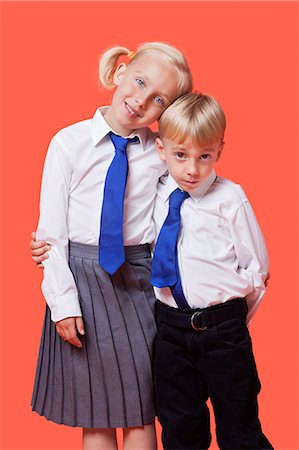 fondo anaranjado - Portrait of young siblings in school uniform with arm around over orange background Foto de stock - Sin royalties Premium, Código: 693-06403577