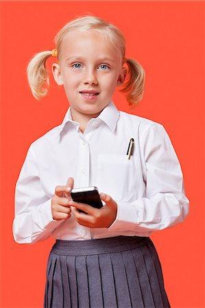 fondo anaranjado - Portrait of a young schoolgirl holding cell phone over blue background Foto de stock - Sin royalties Premium, Código: 693-06403585