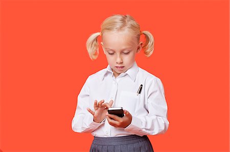 Young school girl reading text messages over orange background Stock Photo - Premium Royalty-Free, Code: 693-06403586