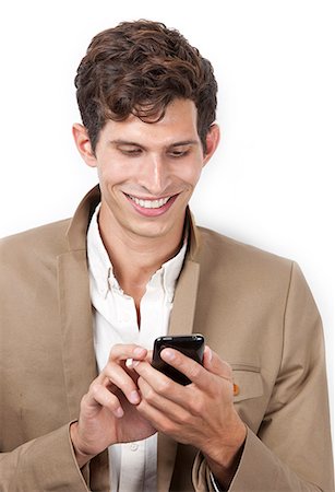 Happy young man text messaging against white background Stock Photo - Premium Royalty-Free, Code: 693-06435754