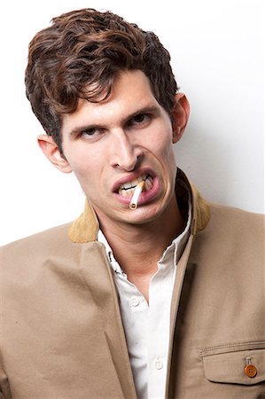 smoking and angry - Portrait of angry young man smoking over white background Foto de stock - Sin royalties Premium, Código: 693-06435752