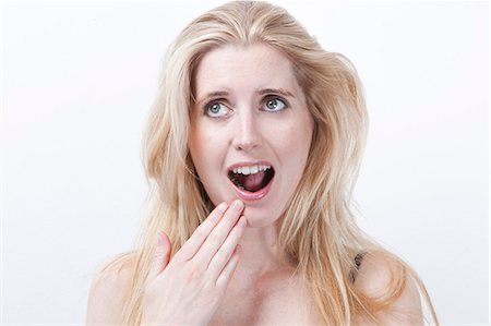 Surprised young woman with mouth open against white background Stock Photo - Premium Royalty-Free, Code: 693-06435776